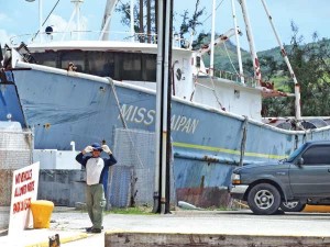 A man waits for colleagues at the Delta dock of the Port of Saipan to post up a sign for no entry to any vehicles or patrons since the dock is structurally unsound. Seen behind him is Miss Saipan’s prow that is now resting on the dock. (Jayson Camacho)
