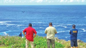 CNMI Homeland Security and Emergency Management special assistant Marvin K. Seman, second from right, operates an unmanned aerial drone as Police Sgt. Thomas Blas and Homeland Security staff Jesse Aldan look on during yesterday’s search efforts for missing Chinese businessman Jian Zhu Deng at Banzai Cliff in Marpi. Also in the photo walking on the cliff line is police officer Jesse Stole. (Ferdie de la Torre)