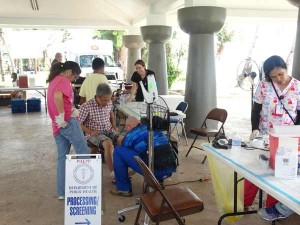 An AmeriCares doctor takes a look at a patient’s feet during the mobile clinic at the Carolinian Utt on Saturday. (Jayson Camacho)