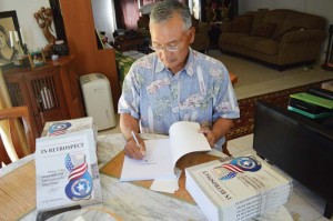 Former CNMI governor and author of In Retrospect Juan N. Babauta signs one of his books at his home. In Retrospect talks about the recent history of the CNMI, along with an analysis and explanation of issues, decisions, and more from the perspective of the sixth governor of the CNMI. (Erwin Encinares)