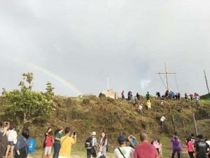 A rainbow appears after volunteers successfully mount the 28-foot tall cross at the peak of Mt. Tapochao and last Friday. (Kimberly A. Bautista)