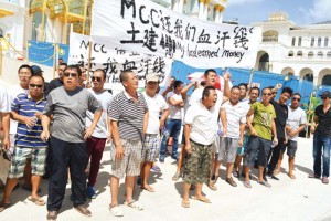 Disgruntled workers demand for their pay along with faster negotiations as they protested yesterday in front of the soon-to-open Imperial Pacific Resort in Garapan. (Erwin Encinares) 