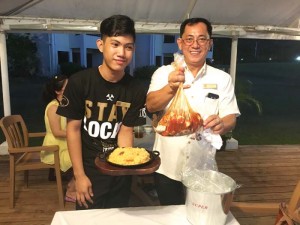 Aqua Resort Club Saipan food and beverage operations manager Rom Manzon, right, serves the Cajun Sea-fest special deluxe bag during the special’s test run last July 18. (Kimberly A. Bautista)