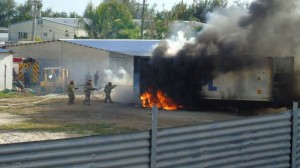Firefighters extinguish the fire that engulfed a container yesterday afternoon in a compound beside a commercial building, where the New XO Market is located along Chalan Pale Arnold Road in Gualo Rai. New XO Market owns the container. Investigators are still looking into the cause of the blaze. (Ferdie de la Torre)