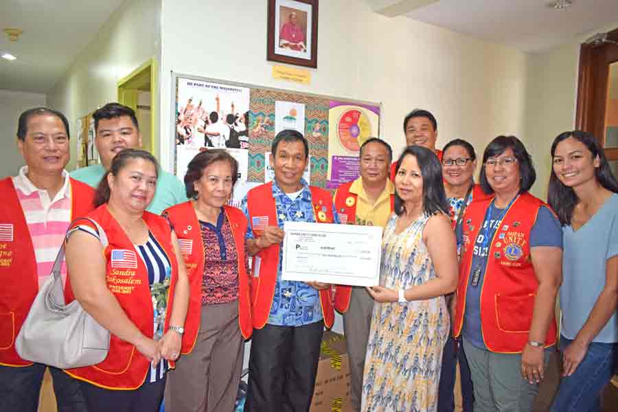 Saipan Unity Lions Club president Willy Barbo, fifth left, hands over the ceremonial check to Karidat Social Services coordinator Emelda Camacho in yesterday’s presentation. SULC members and past officers are the others in the photo. (Jon Perez)