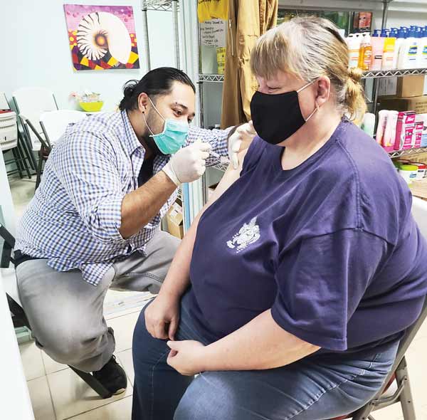 Brabu Pharmacy technician RJ Dris administers a vaccine/immunization shot to a patient. 