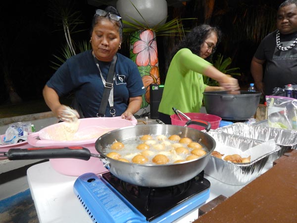 Vicenta Igisomar, left, prepares buñelos while Alice Romolor, second from right, prepares island-style sukiyaki in front of a small crowd during “Island Cuisine Night” at the Carolinian Utt in Garapan.
