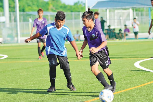 A Hopwood Middle School player, right, tries to navigate his way out of a Saipan International School defender during their game in the NMIFA-PSS Interscholastic Soccer League 
