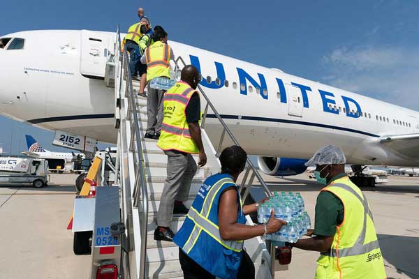 United Airlines employees help pass food stuff to be loaded on a plane for the benefit of Afghan refugees. 