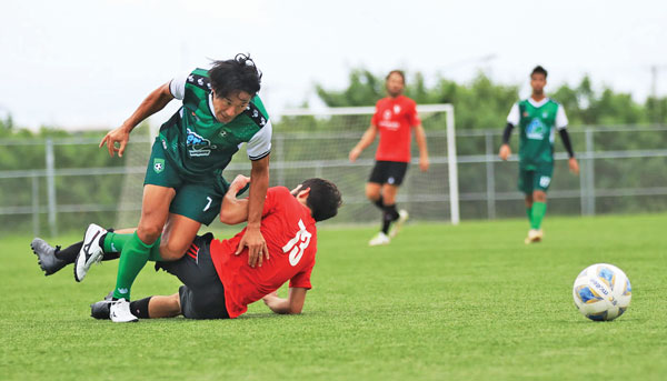 TanHoldings Footballl Club’s Michiteru Mita, left, seen here colliding with a Paire Football Club defender