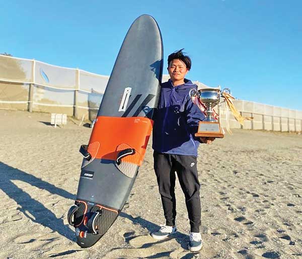 Wataru Tajima shows off his trophy and windsurfing board